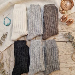 May include: A set of six ribbed knit socks in various neutral colours including cream, light grey, dark grey, brown, and black. The socks feature a thick, textured vertical ribbing pattern throughout the leg and foot, with a reinforced cuff at the top.