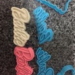 May include: Four cookie cutters in different colors, blue, pink, yellow, and light blue, with the word "Barbie" written in a cursive font.