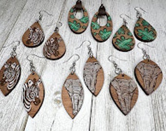 May include: Assortment of eight wooden dangle earrings with various animal and leaf designs. The earrings are in the shapes of teardrops and ovals. The designs include zebra, elephant, and green leaves.
