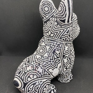 May include: A black and white ceramic figurine of a French bulldog with a geometric pattern. The figurine is made of small, white beads that are arranged in a complex design.