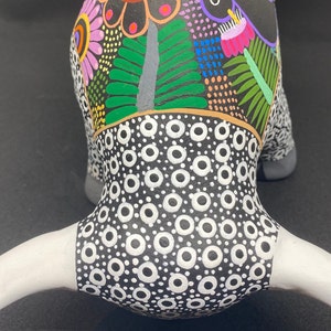 May include: A black and white ceramic bull figurine with a colorful floral design on the head. The bull has white horns and a black and white polka dot pattern on the body.