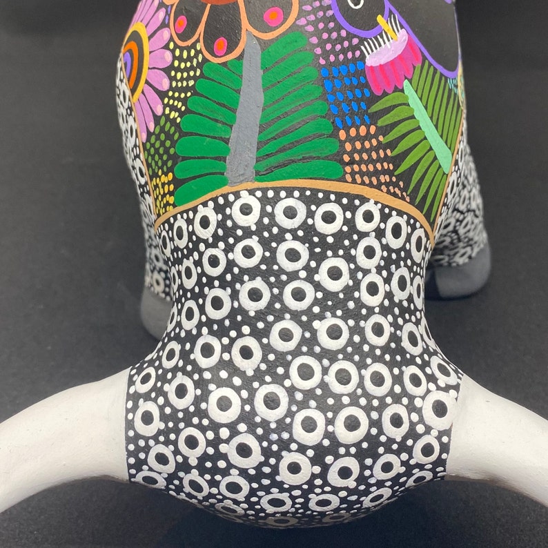 May include: A black and white ceramic bull figurine with a colorful floral design on the head. The bull has white horns and a black and white polka dot pattern on the body.