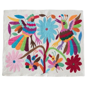 May include: A white cotton fabric with colorful embroidery of two birds, flowers, and butterflies. The birds have long, colorful tails and are perched on a branch. The flowers are in shades of pink, blue, and red. The butterflies are in shades of purple, orange, and yellow.