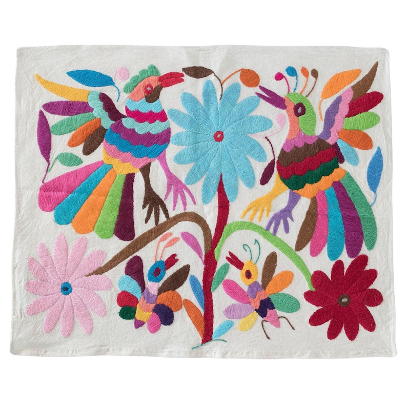 May include: A white cotton fabric with colorful embroidery of two birds, flowers, and butterflies. The birds have long, colorful tails and are perched on a branch. The flowers are in shades of pink, blue, and red. The butterflies are in shades of purple, orange, and yellow.
