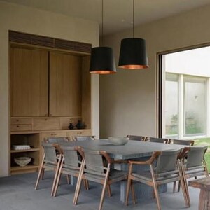 May include: A dining room with a large wooden cabinet, a square table with gray chairs, and two black pendant lights with copper interiors.