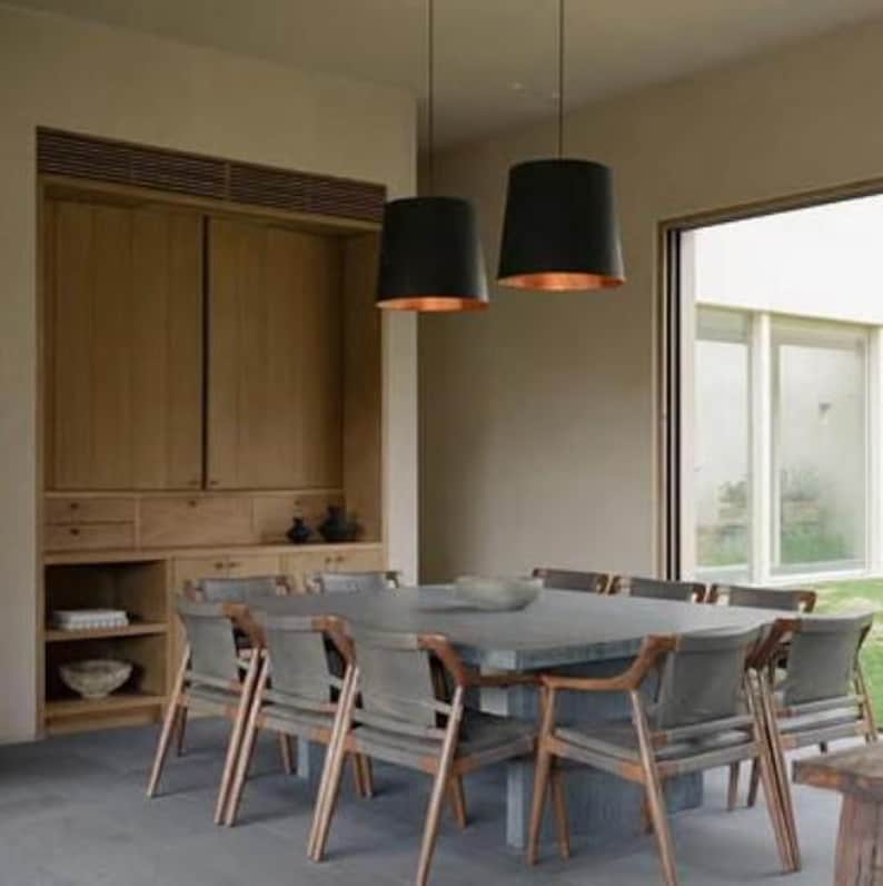 May include: A dining room with a large wooden cabinet, a square table with gray chairs, and two black pendant lights with copper interiors.