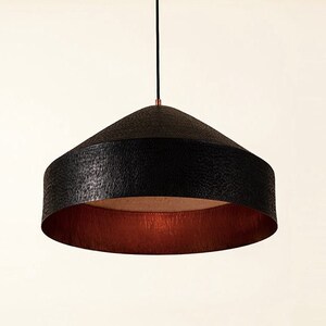 May include: Black pendant light with a hammered metal shade and a copper interior.