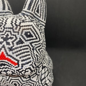 May include: A black and white beaded animal figurine with a red nose. The figurine is made of small, round beads that are arranged in a geometric pattern.