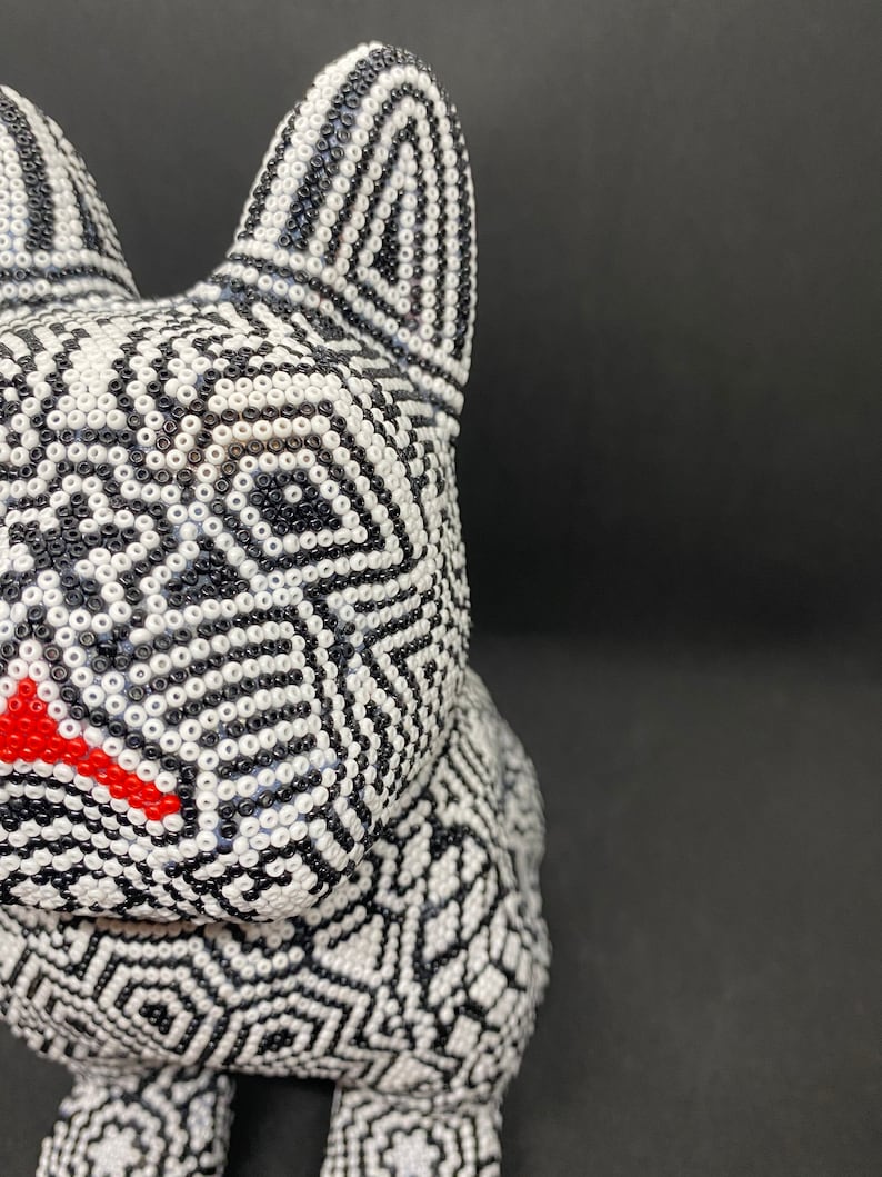 May include: A black and white beaded animal figurine with a red nose. The figurine is made of small, round beads that are arranged in a geometric pattern.