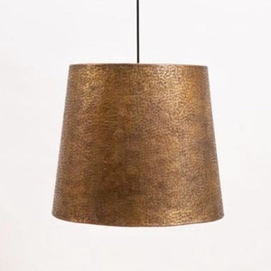 May include: A hammered brass pendant light fixture with a wide, round shade.