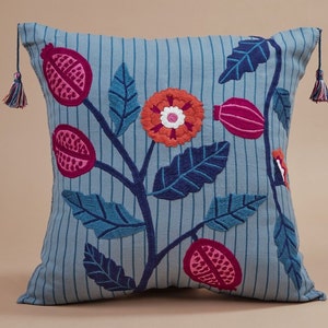 May include: A blue and white striped pillow with embroidered flowers and leaves in shades of pink, red, and orange.