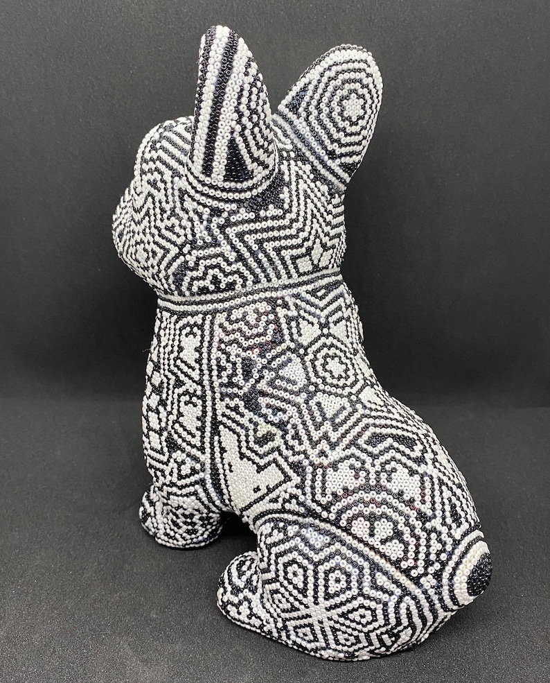 May include: A black and white ceramic figurine of a dog with a geometric pattern. The figurine is sitting on a black surface.