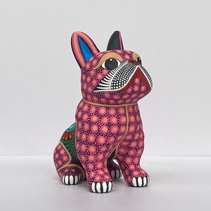 以下が含まれることがあります： ピンクと黒の手描きセラミック製フレンチブルドッグの置物。置物は黒と白のドットと黒い鼻で詳細なデザインが施されています。