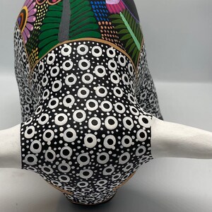 May include: A black and white ceramic bull figurine with a colorful floral pattern on the head and horns. The bull has a white horn and a black and white polka dot pattern on the body.