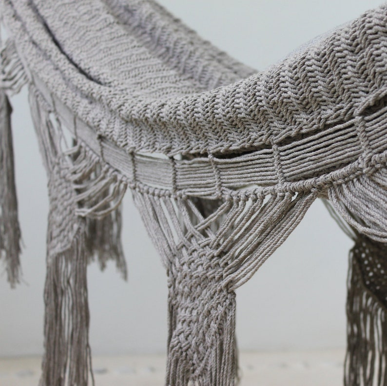 Puede incluir: Una hamaca beige con un patr&oacute;n tejido y detalles de flecos. La hamaca est&aacute; hecha de fibras naturales y tiene un estilo relajado y bohemio.