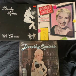 May include: Three vintage vinyl records featuring Dorothy Squires. The first record is black with white text and a black and white image of a clown. The second record is white with black text and a colour image of Dorothy Squires. The third record is black with white text and a colour image of Dorothy Squires.
