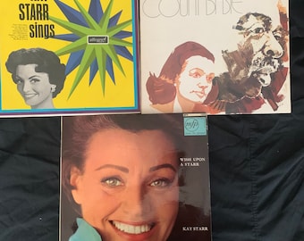 Pode incluir: Três discos de vinil com Kay Starr. O primeiro disco é amarelo com um design de estrela verde e o texto "Kay Starr Sings". O segundo disco é branco com o texto "Kay Starr & Count Basie" e um logotipo de estrela dourada. O terceiro disco é preto com o texto "Wish Upon A Starr" e "Kay Starr".