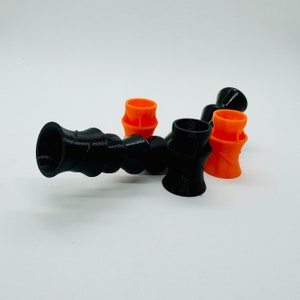 May include: A black and orange flexible pipe with four sections. The pipe is made of plastic and has a smooth finish. The pipe is designed to be used for a variety of purposes, such as connecting hoses or pipes.