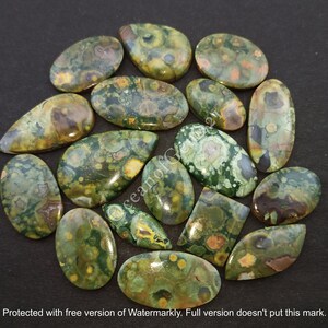 Puede incluir: Una colecci&oacute;n de 17 cabujones de jaspe oce&aacute;nico verde, marr&oacute;n y amarillo. Los cabujones son de varias formas y tama&ntilde;os, con una superficie pulida y lisa.