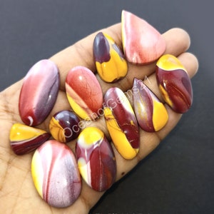 Puede incluir: Una colección de diez cabujones de piedra preciosa pulidos, coloridos y con patrones. Los cabujones son de varias formas, incluyendo ovaladas y de lágrima. Los colores incluyen rojo, amarillo, blanco y marrón.