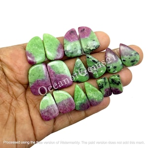 Könnte beinhalten: Eine Sammlung polierter Rubin-Zoisit-Edelsteine in verschiedenen Formen, darunter Tropfen, Rechtecke und abgerundete Formen. Die Steine zeigen eine Mischung aus grünen und tiefrosa Farbtönen, mit dem Text "OceanofGems21" sichtbar. Die Edelsteine werden in einer Hand gehalten.