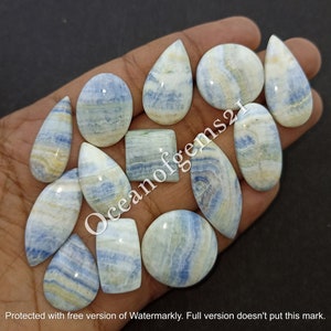 May include: A collection of 12 blue and white cabochon gemstones with a variety of shapes, including oval, teardrop, and square. The stones have a swirling pattern of blue and white.