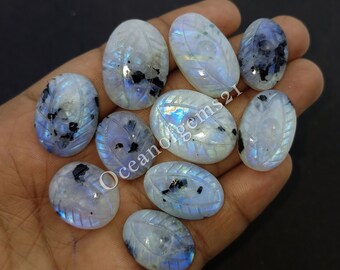 May include: Nine oval-shaped moonstone cabochons with carved leaf designs. The stones are a milky white with iridescent blue and black flecks.