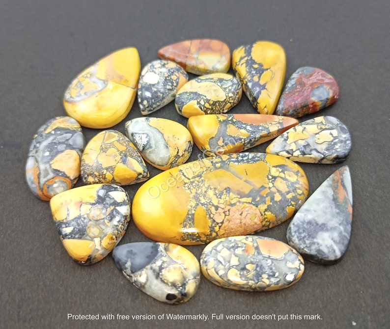 Puede incluir: Una colecci&oacute;n de 14 cabujones de piedras preciosas amarillas, marrones y negras. Los cabujones tienen forma de l&aacute;grima y ovalada y presentan un patr&oacute;n moteado.