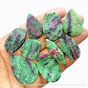 May include: A collection of eight green, pink, and black gemstone cabochons in a teardrop shape. The stones are smooth and polished.