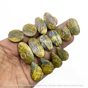 May include: A collection of 12 oval and teardrop shaped gemstone beads. The beads are a mix of yellow and green with a striated pattern.