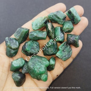 Può includere: Una collezione di pietre preziose di smeraldo grezzo di colore verde. Gli smeraldi sono di varie dimensioni e forme, alcuni hanno una tonalità verde più scura.
