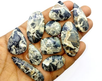 May include: A collection of nine black, white, and brown agate cabochons with a variety of shapes and sizes. The cabochons have a swirling, marbled pattern.