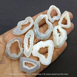 May include: A collection of ten white agate slices with a natural hole in the centre. The agate slices are translucent and have a smooth, polished surface.