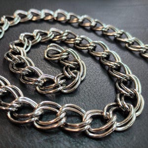 Peut inclure: Un collier en chaîne argentée avec un design épais et torsadé. La chaîne est composée de plusieurs brins de métal qui sont entrelacés pour créer un look unique et accrocheur.