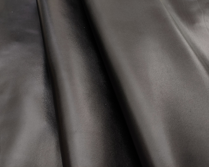 Smooth full grain black cowhide leather pieces for bags and crafts, shown folded to highlight glossy texture.