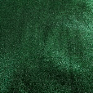 Puede incluir: Primer plano de un material de cuero verde esmeralda texturizado. La superficie tiene un brillo sutil y un patr&oacute;n fino e irregular, lo que sugiere una veta natural. El color es un verde profundo y rico.