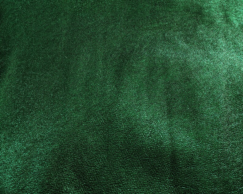 Puede incluir: Primer plano de un material de cuero verde esmeralda texturizado. La superficie tiene un brillo sutil y un patr&oacute;n fino e irregular, lo que sugiere una veta natural. El color es un verde profundo y rico.