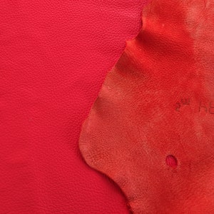 May include: Two pieces of red leather, one smooth and one textured. The textured leather has a small hole in it.