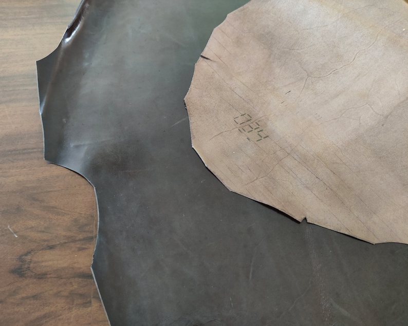May include: Two pieces of leather, one dark brown and one light brown. The light brown piece has the number "0055" written on it.