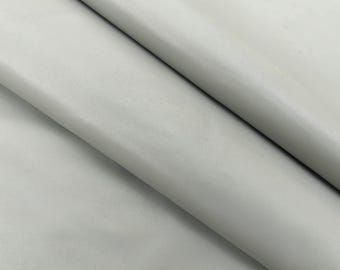 May include: A close-up of a light gray leather fabric. The fabric has a smooth, slightly textured surface.