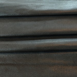 Może przedstawiać: Zbliżenie czarnego materiału o fakturowanej, żwirowej powierzchni. Materiał jest złożony w kilka warstw, tworząc miękki, drapowany efekt.