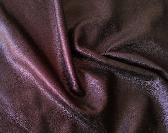 Puede incluir: Primer plano de una tela de color morado oscuro con un brillo sutil. La tela está arrugada y tiene una superficie texturizada.