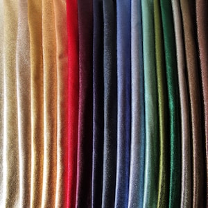 Puede incluir: Una colecci&oacute;n de muestras de tela en una variedad de colores, incluyendo blanco, dorado, rojo, azul marino y verde. La tela tiene un brillo sutil, y los pliegues crean sombras que resaltan los diferentes tonos. La disposici&oacute;n muestra la gama de colores disponibles.
