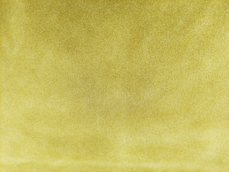 May include: A close-up of a textured, light yellow fabric. The fabric has a soft, fuzzy texture.