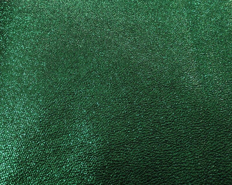 Puede incluir: Primer plano de una superficie texturizada de color verde esmeralda. El material tiene un brillo sutil, con una textura ligeramente rugosa e irregular. El color es un verde intenso y rico, con variaciones de tono.