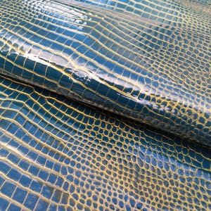 May include: Close-up of a blue and gold textured fabric with a crocodile skin pattern.