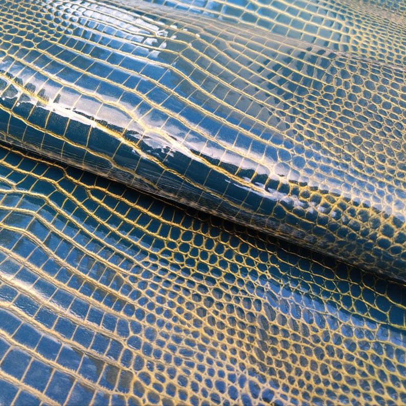 May include: Close-up of a blue and gold textured fabric with a crocodile skin pattern.