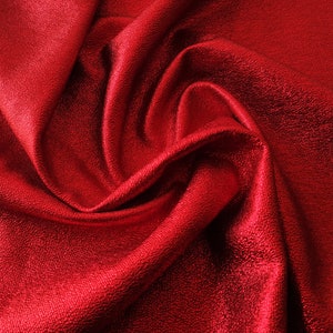 Peut inclure: Gros plan sur un tissu rouge avec une texture lisse et brillante. Le tissu est plié et drapé, créant des lignes douces et fluides.