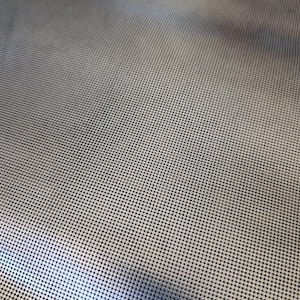 Könnte beinhalten: Ein metallisch silberner Netzstoff mit einem dichten, gleichmäßigen Muster aus kleinen, kreisförmigen Perforationen. Das Material hat eine reflektierende, glatte Oberfläche mit einer konsistenten Gitterstruktur, die einen Lichtverlauf erzeugt.