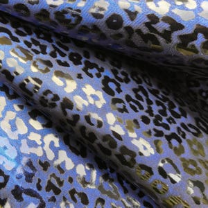 Puede incluir: Tela azul con estampado de leopardo plateado y negro.